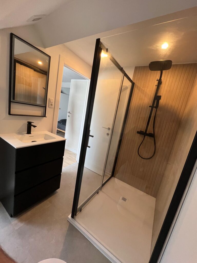 Douche à profilés noirs et meuble vasque suspendu à proximité de la chambre
