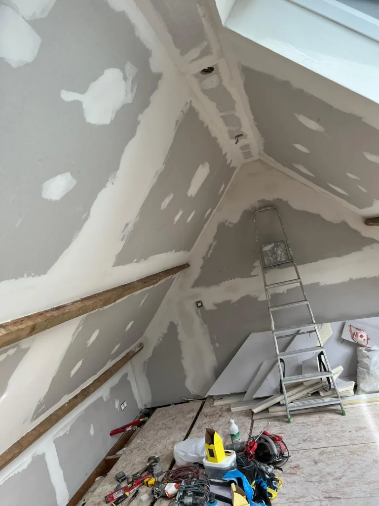 Plaques de plâtre sous rampants avec joints et points de fixation enduits, avant finition.