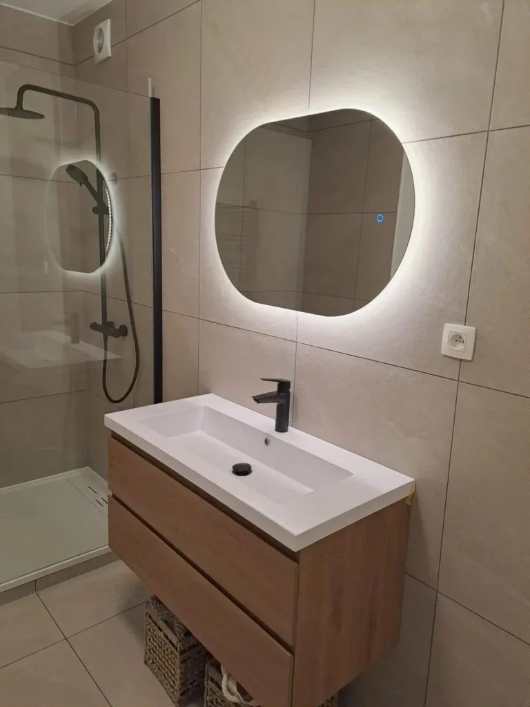 Meuble vasque suspendu finition bois avec deux tiroirs, vasque blanche, robinet noir et miroir rétroéclairé.