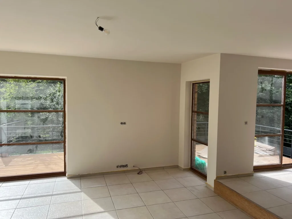 Murs et plafond repeints dans une pièce avec de grandes baies vitrées et un sol carrelé.