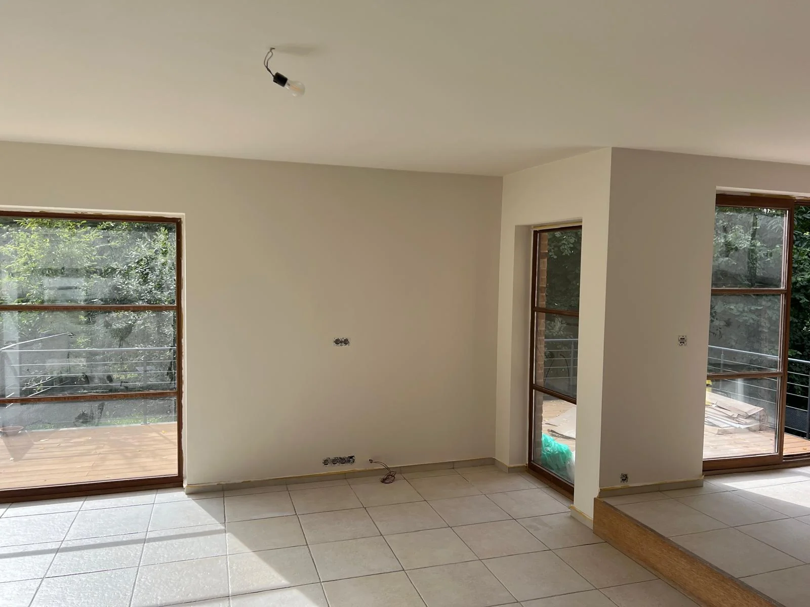 Murs et plafond repeints dans une pièce avec de grandes baies vitrées et un sol carrelé.